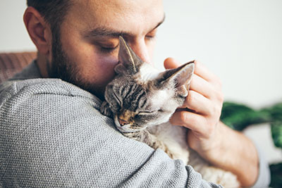 man holding a cat and kissing it 